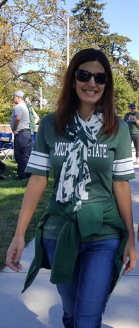 Woman wearing Michigan State apparel at a tailgate.