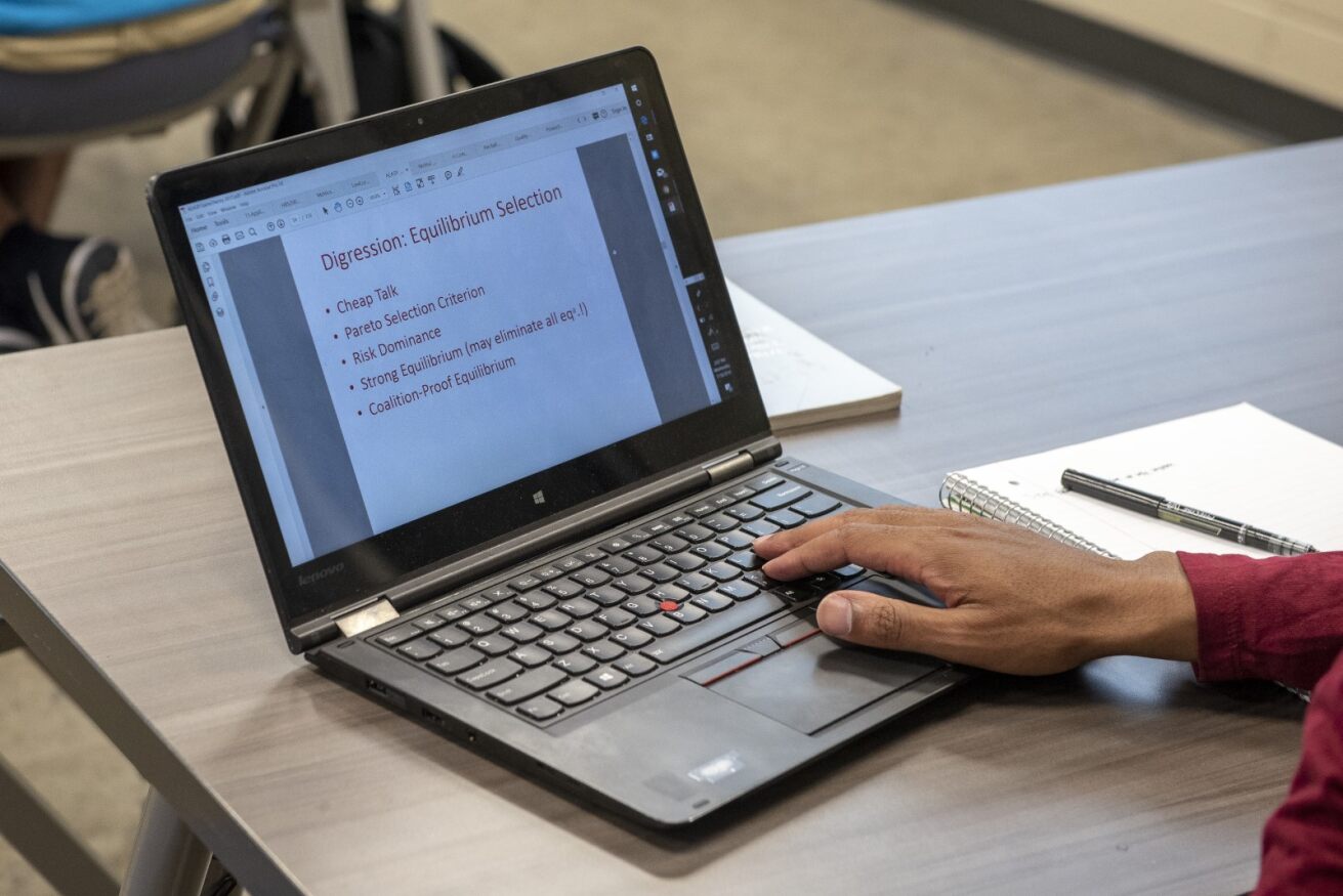 桌上的笔记本电脑，棕色的手在打字。 
