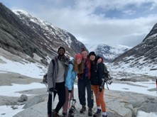 A group of women and male students with snow and mountains behind them. 